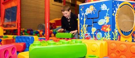 Un niño jugando con bloques de construcción coloridos en un espacio de juego interior.