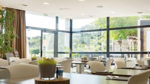Un comedor moderno con ventanas amplias, sillas blancas y mesas.