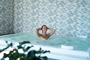 Una persona en un jacuzzi con un muro estampado al fondo.