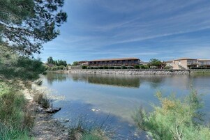 Un hotel con un edificio grande y una masa de agua al frente.