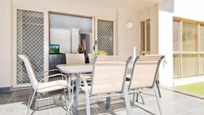 A dining area with a table and chairs, a kitchen in the background, and a view of a garden. - Bay Hideaway Resort (Eli Waters)