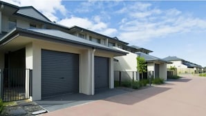 A row of modern residential buildings with garage doors, a paved driveway, and a clear sky. - Bay Hideaway Resort (Eli Waters)