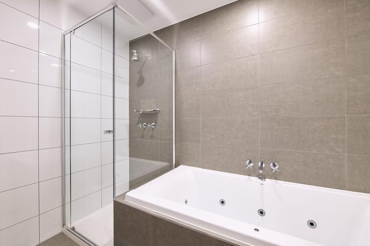 A modern bathroom with a glass shower enclosure, a freestanding bathtub, and tiled walls.