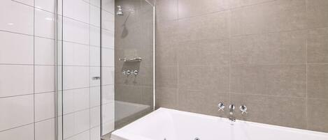 A modern bathroom with a glass shower enclosure, a freestanding bathtub, and tiled walls.