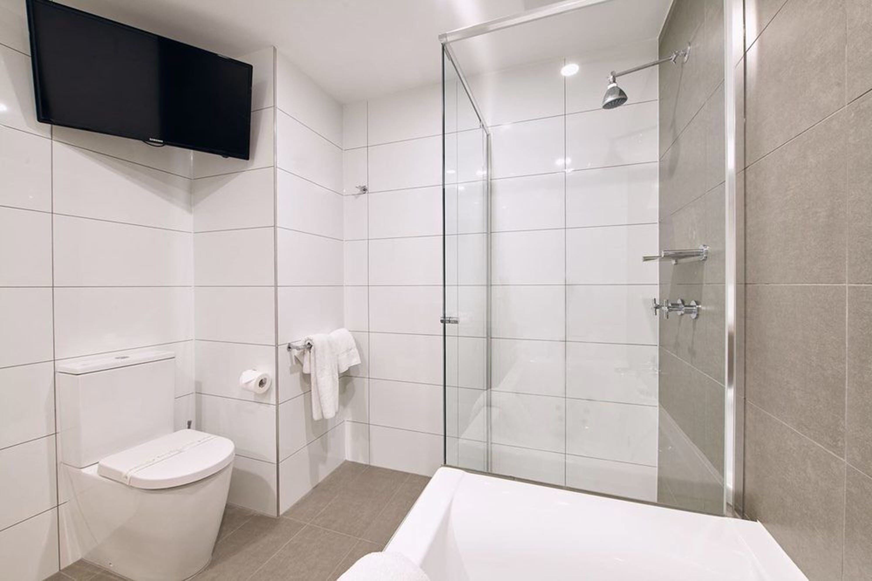 A modern bathroom with a toilet, shower, and bathtub.