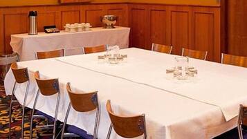 A conference room with a long table set for a meeting, equipped with chairs, a water dispenser, and a coffee pot.
