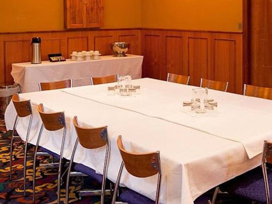 A conference room with a long table set for a meeting, equipped with chairs, a water dispenser, and a coffee pot.