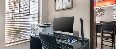Um espaço de escritório moderno com mesa, computador e impressora.