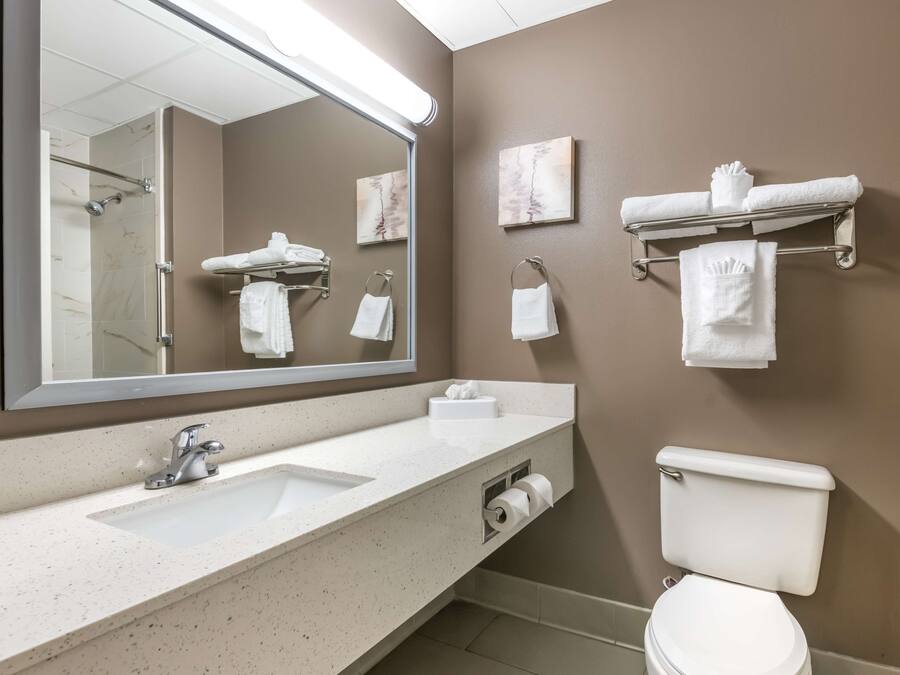 Ein modernes Badezimmer mit großem Spiegel, Waschbecken, Toilette und Handtuchhaltern.