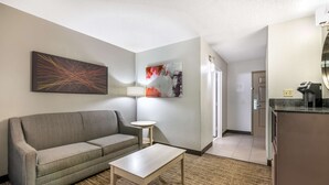 Habitación de hotel con sofá, una mesita, lámpara y cuadros en la pared.
