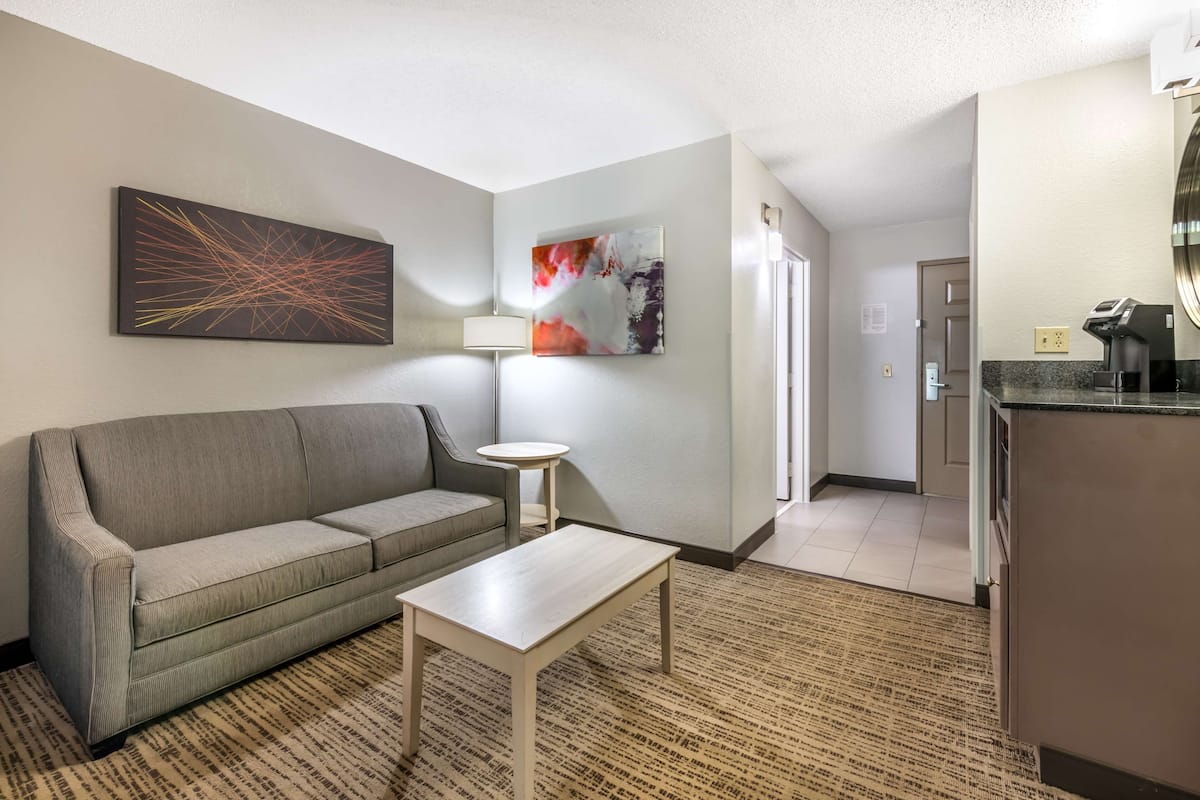 Une chambre d’hôtel avec un canapé, une petite table, une lampe et des œuvres d’art accrochées au mur.