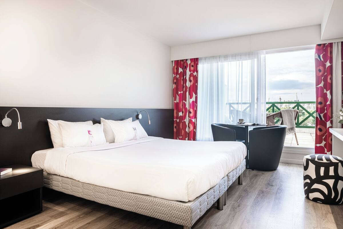 Une chambre d’hôtel avec un lit, une table de chevet, une chaise et une vue sur la ville.