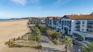 Ein Hotel direkt am Strand mit einer Reihe von Gebäuden, einem Sandstrand und einem klaren Himmel.