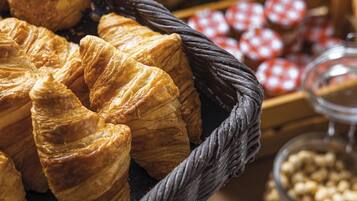Diversitat de pa i pastissos, com ara croissants, disposats sobre una taula amb cistells i pots de fruits secs.