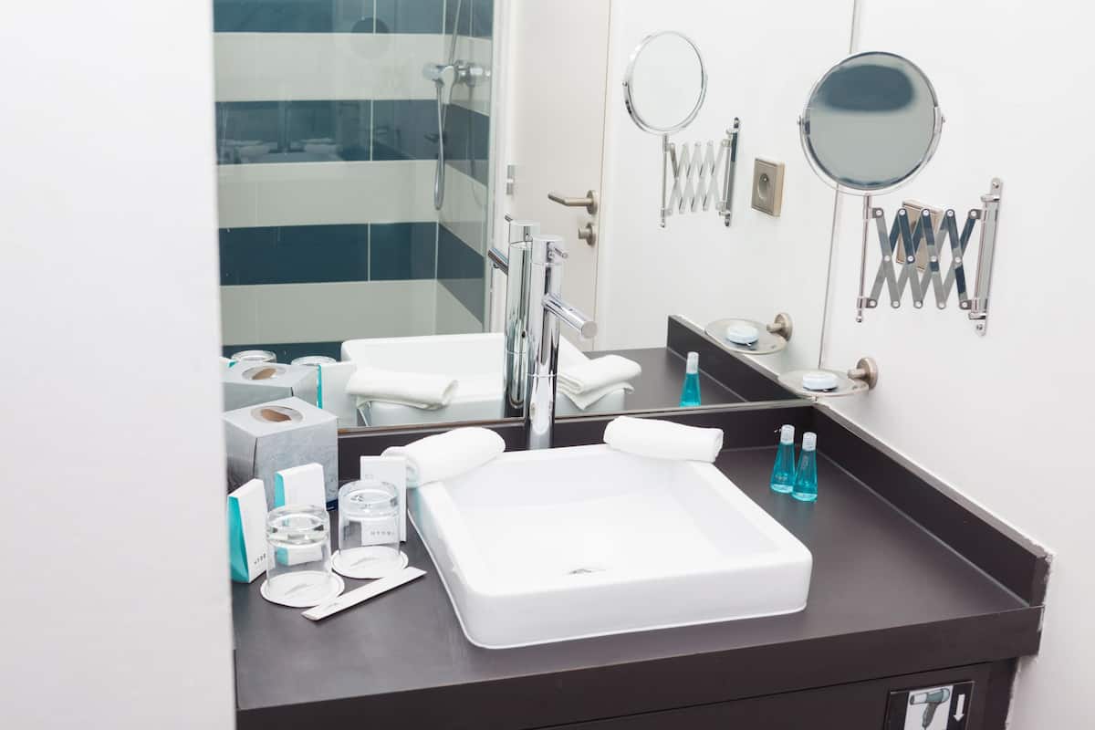 Une salle de bain moderne avec un grand miroir, deux lavabos et une douche.