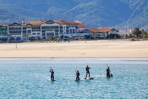 A beachfront hotel with multiple stories, a sandy beach, and a clear view of the sea.