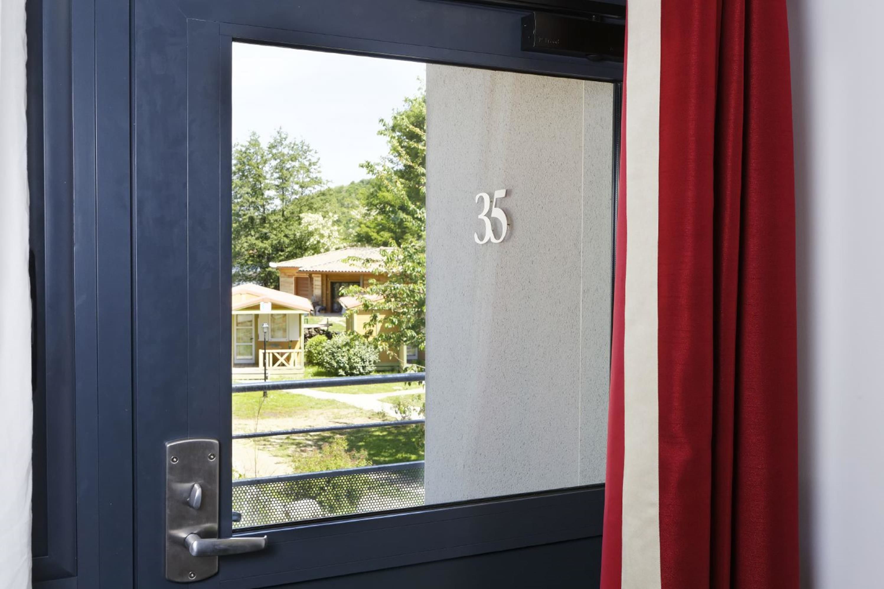 A door with a number "35" and a view of a garden and outdoor seating area.