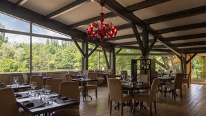 A restaurant with wooden tables and chairs, large windows, and a red chandelier. - Hotel du Lac Foix (Foix)