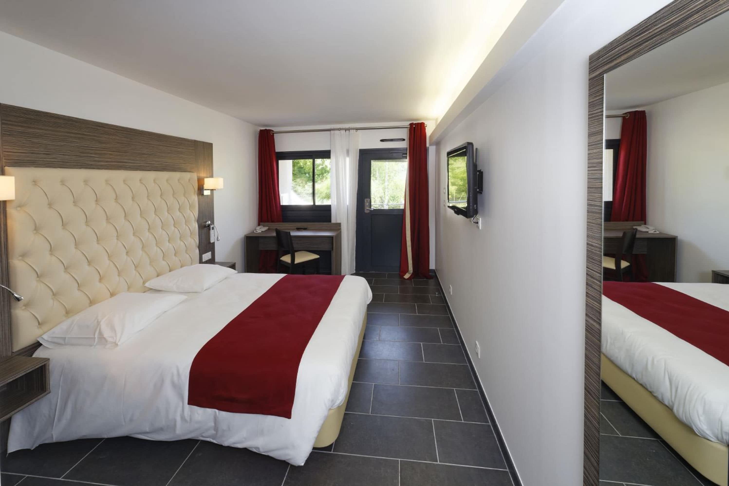Een hotelkamer met een groot bed, een bureau en een spiegel.