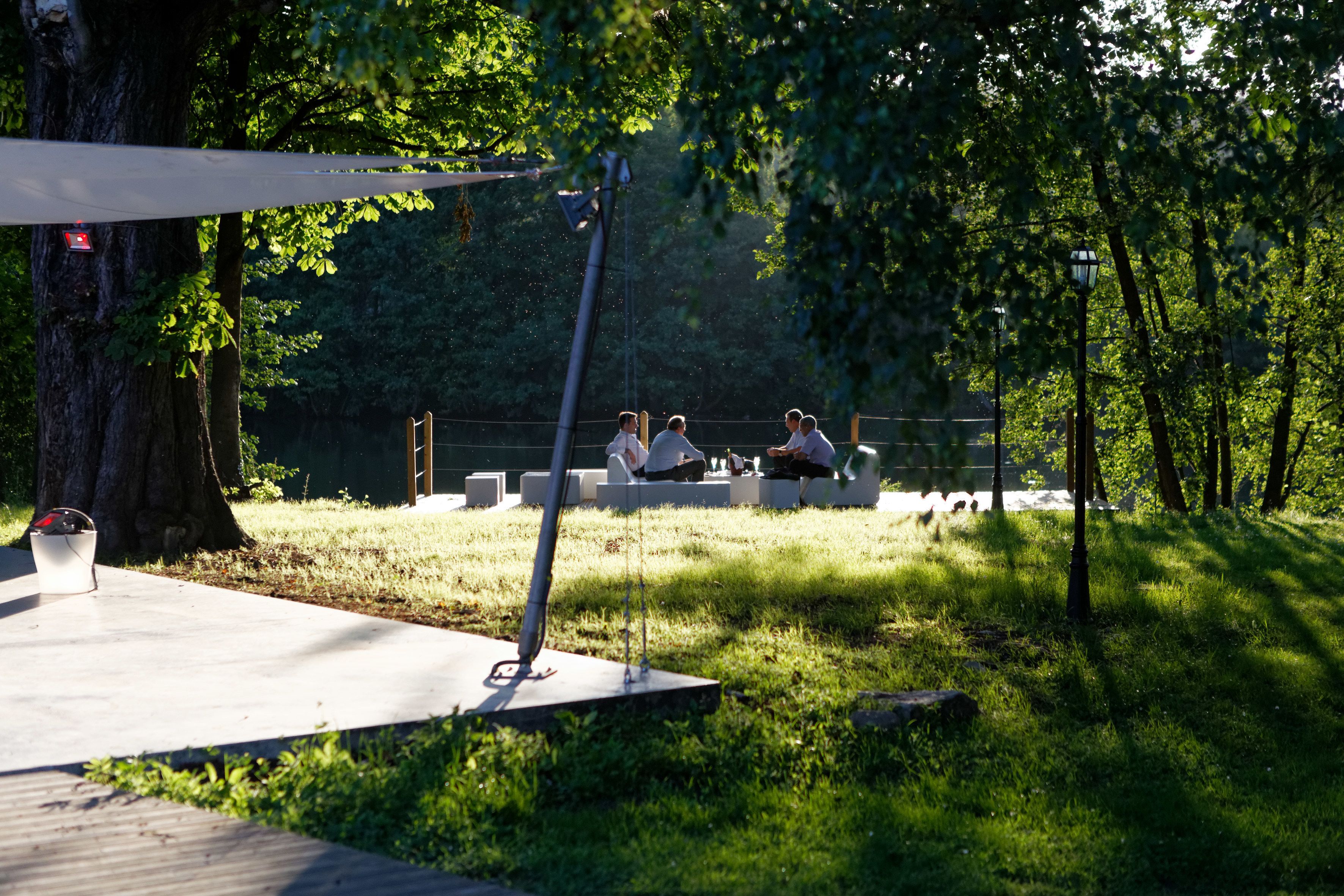 An outdoor seating area with a modern design, surrounded by trees and a grassy area.