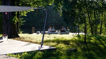 Un área de estar al aire libre con diseño moderno, rodeada de árboles y césped.