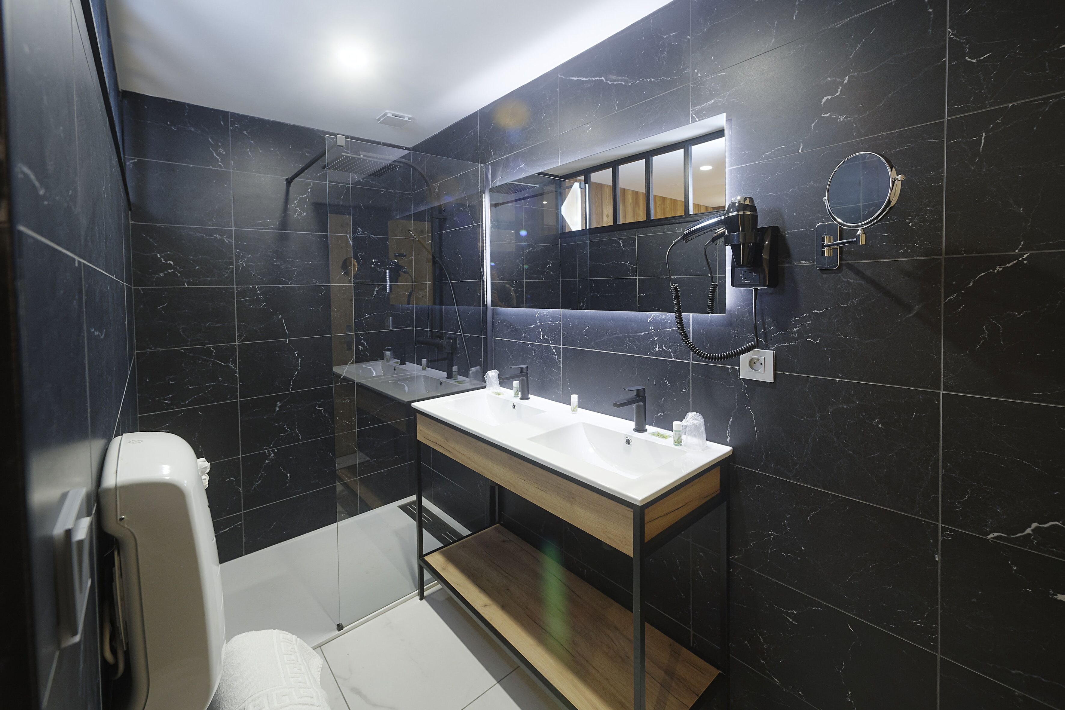 Une salle de bain moderne avec un double vasque, un miroir et une douchette à main.