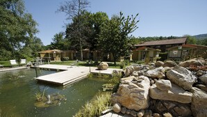 A lakeside hotel with wooden docks, a pond, and large rocks. - Hotel du Lac Foix (Foix)
