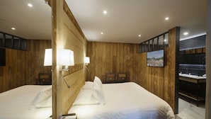 A hotel room with two beds, wooden paneling, a TV, and a bathroom with a mirror and sink. - Hotel du Lac Foix (Foix)