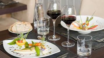 A dining table with plates of food, wine glasses, and cutlery.