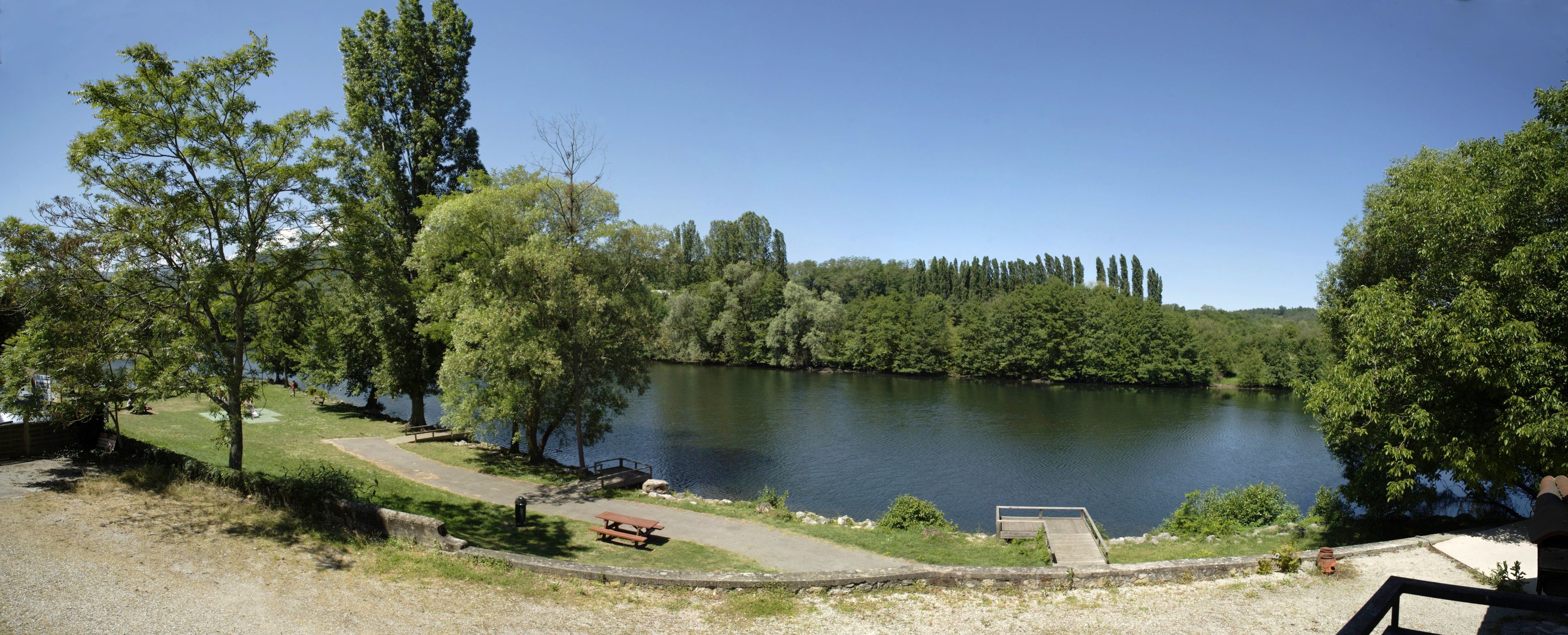 A lakeside park with picnic areas, a walking path, and a dock.