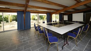 A conference room with a long table, blue chairs, and a projector screen.