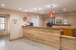 A reception desk with a wooden counter, a clock, and a door in the background.