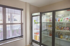 A room with a window, a refrigerator, and a vending machine.