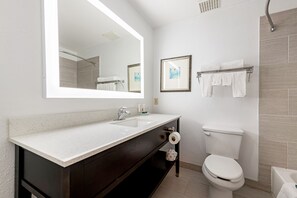 A modern bathroom with a large mirror, two sinks, a toilet, and a towel rack.