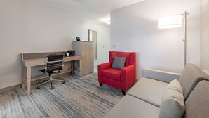 A hotel room with a desk, a red armchair, a sofa, and a lamp. - SureStay by Best Western Lewisville Dallas (Lewisville)