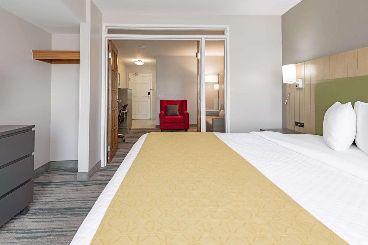 A hotel room with a large bed, a desk, a chair, and a wardrobe.