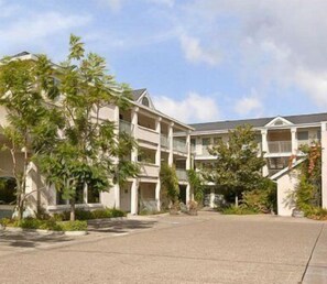Ein mehrstöckiges Hotel mit Innenhof, Balkonen und umgebender Bepflanzung.