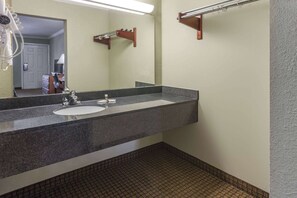 Bathroom features a granite countertop sink and mirror, with a towel rack and patterned tile flooring.
