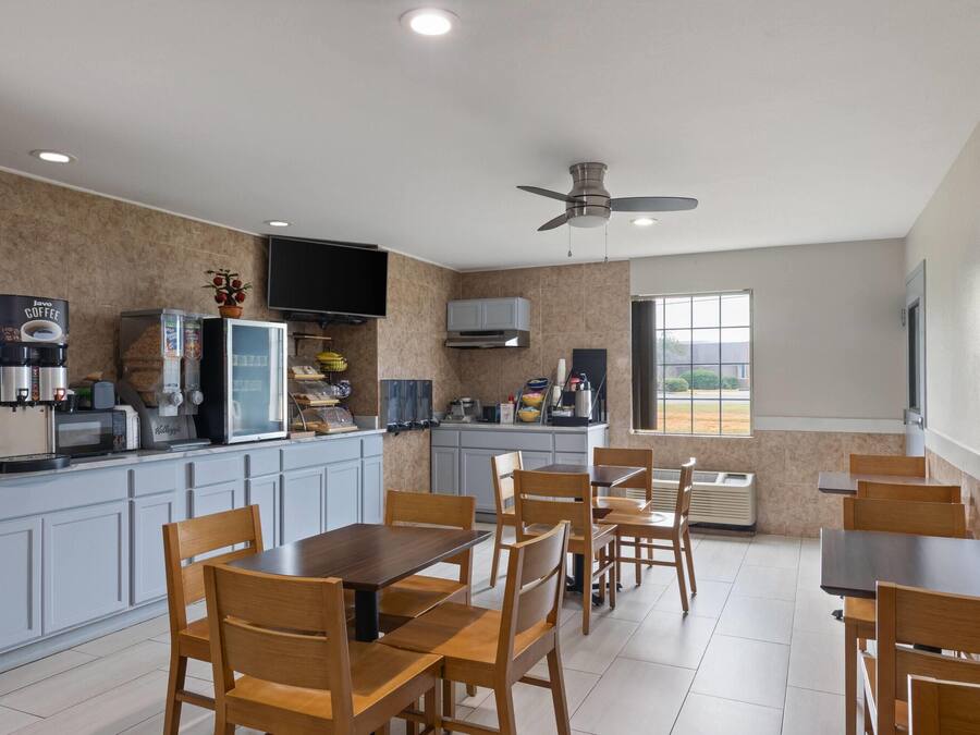 A modern kitchen with grey cabinets, a coffee station, and a dining area with wooden tables and chairs.