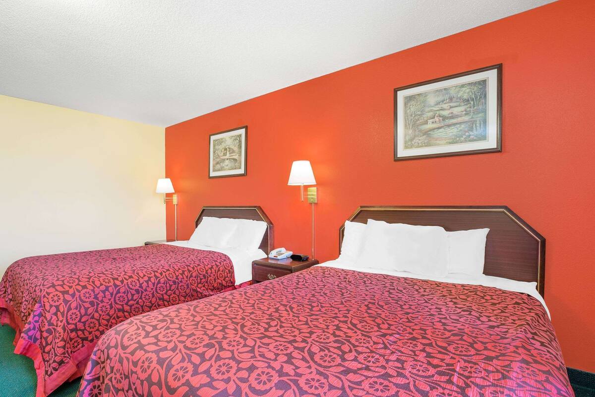 A hotel room with two beds, each with a patterned bedspread, bedside lamps, and framed artwork on the walls.