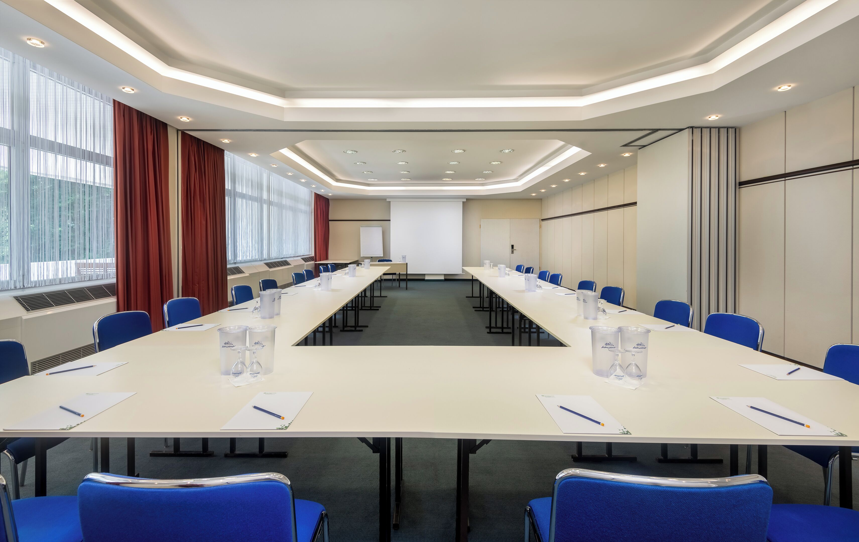 A conference room with a long table, blue chairs, and a whiteboard.