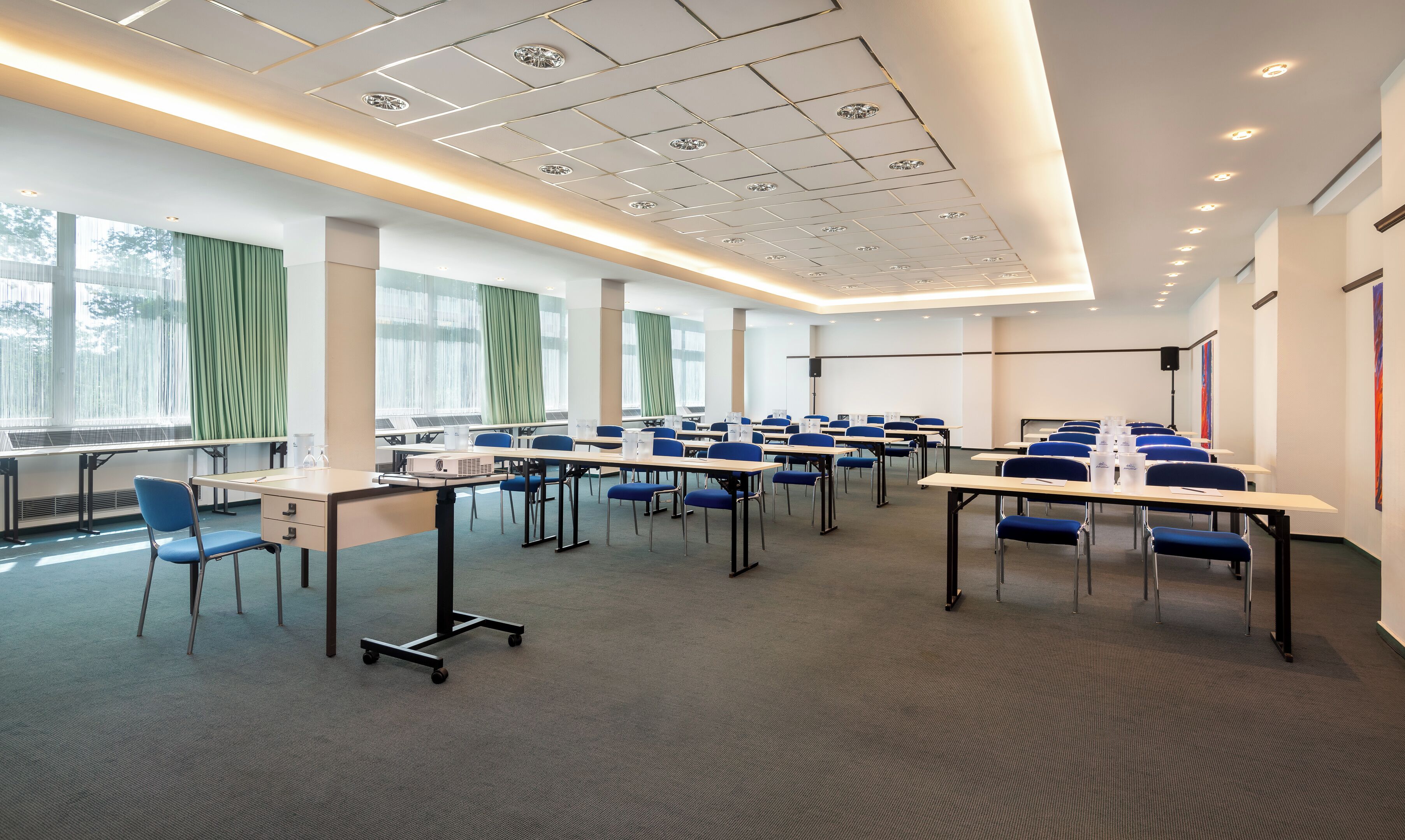 A conference room with tables, chairs, and a projector.