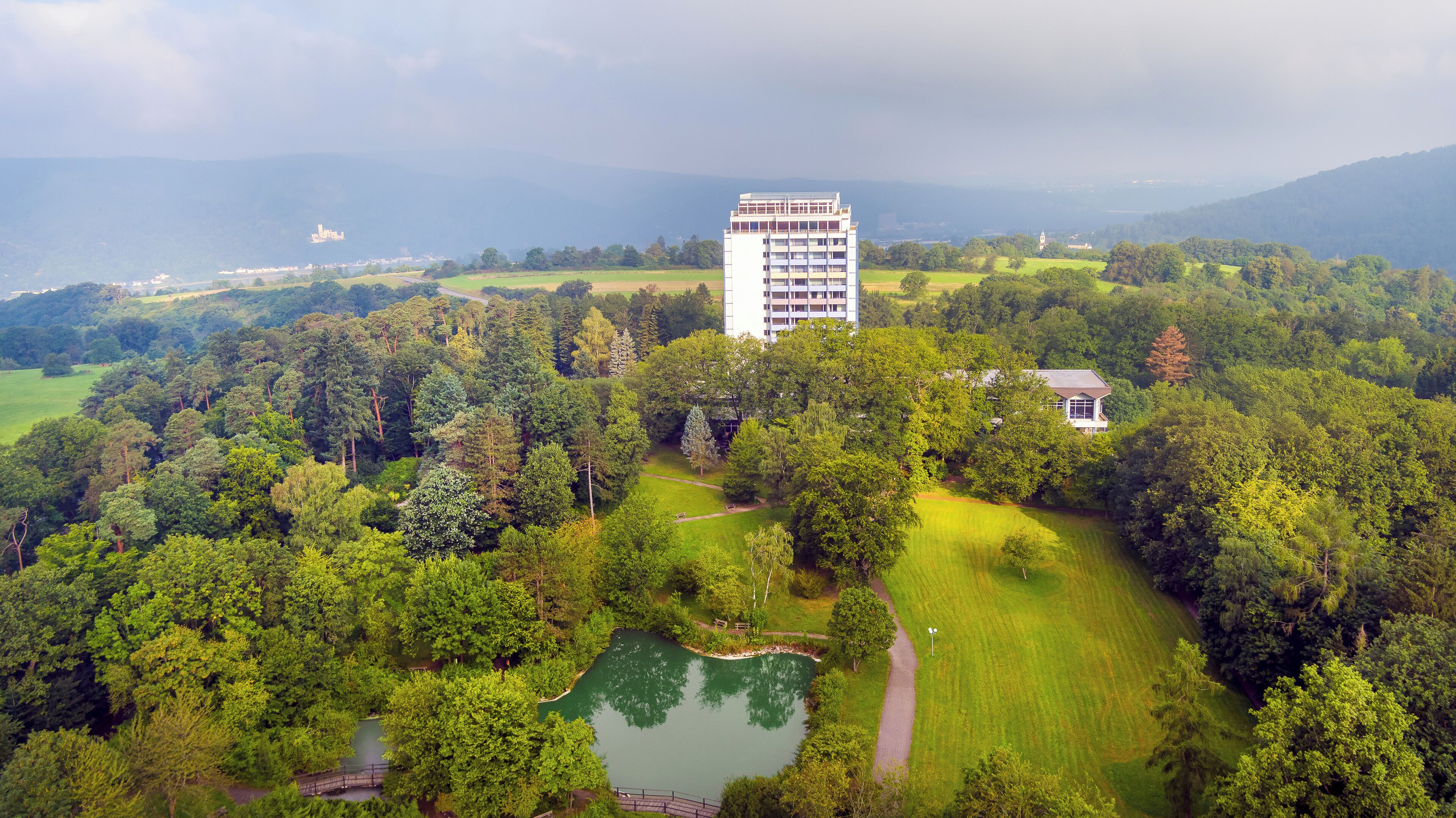 Ein großes Gebäude, umgeben von üppigem Grün, einem Teich und einem Golfplatz.