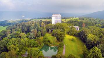 Ein großes Gebäude, umgeben von üppigem Grün, einem Teich und einem Golfplatz.