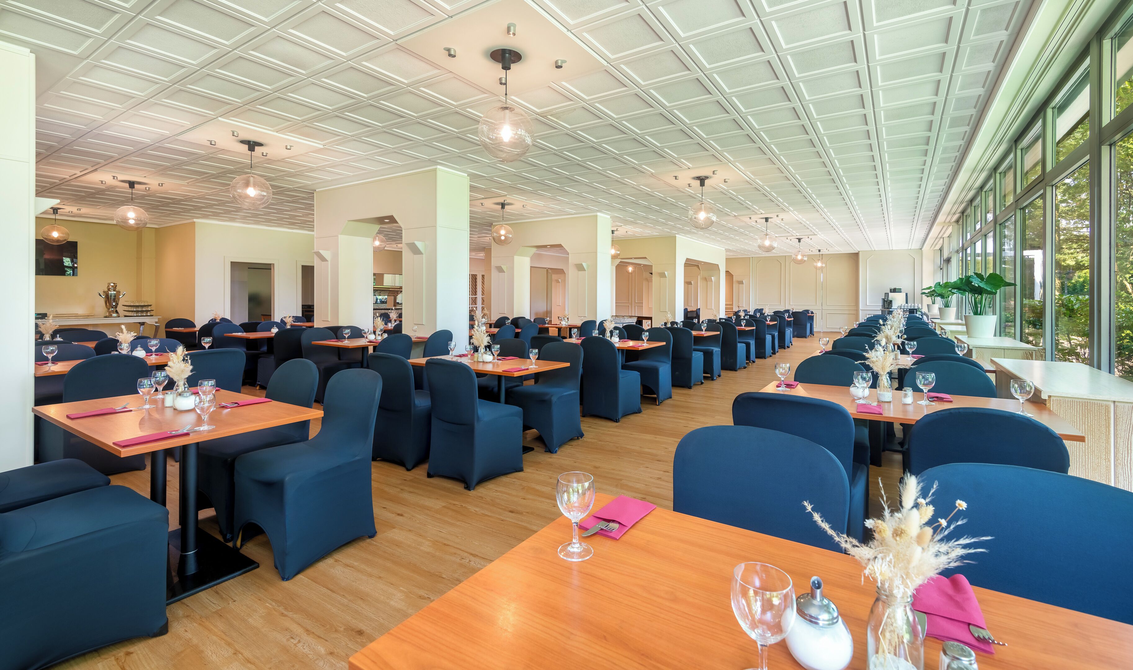 Un restaurante espacioso con techos altos, iluminación moderna y amplios ventanales que ofrecen vistas al exterior.