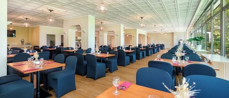 Un restaurante espacioso con techos altos, iluminación moderna y amplios ventanales que ofrecen vistas al exterior.
