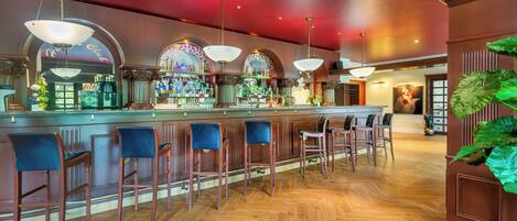A bar area with wooden bar stools, a bar counter, and hanging pendant lights.