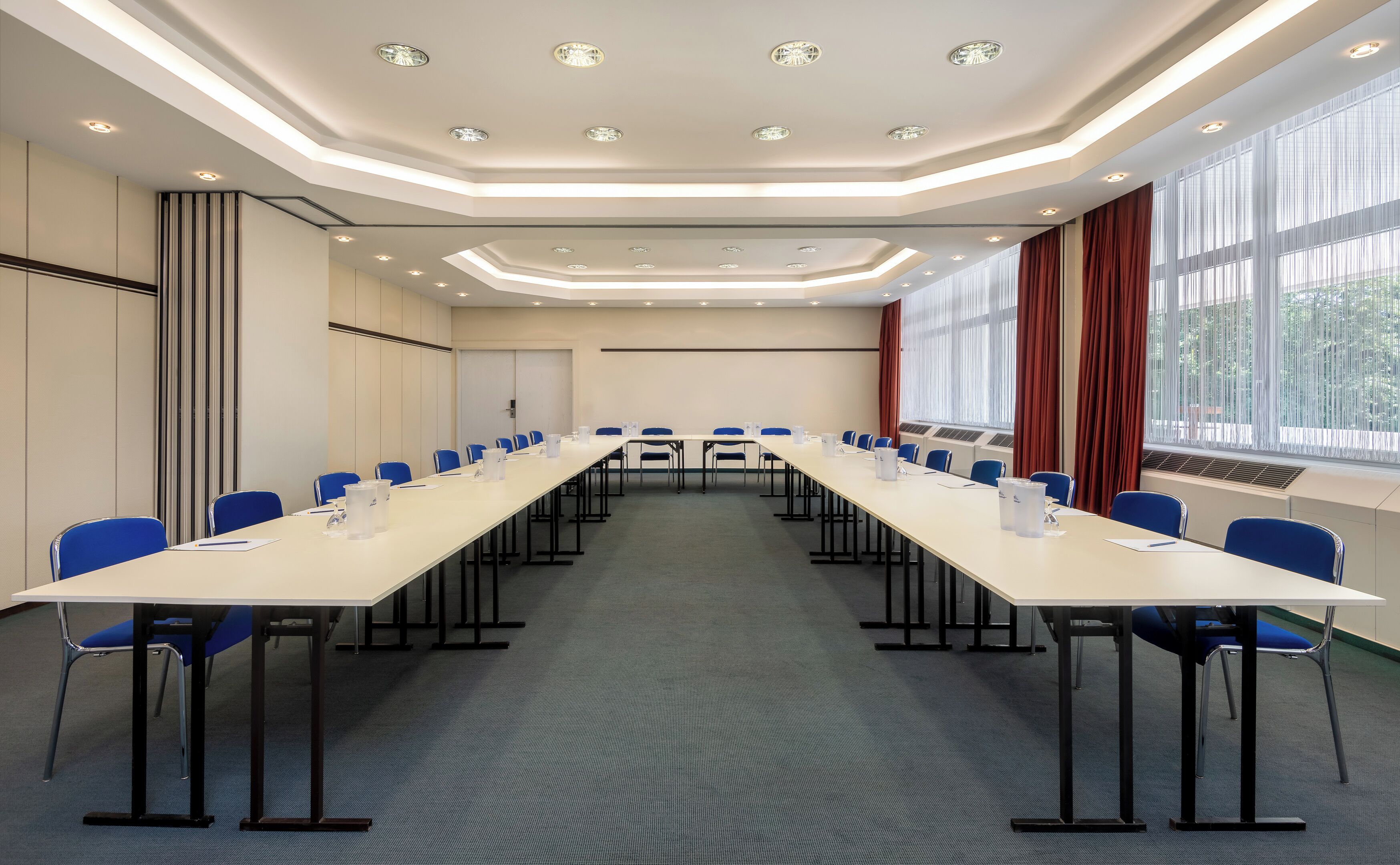 Una sala de conferencias con una larga mesa, sillas azules y piso alfombrado.