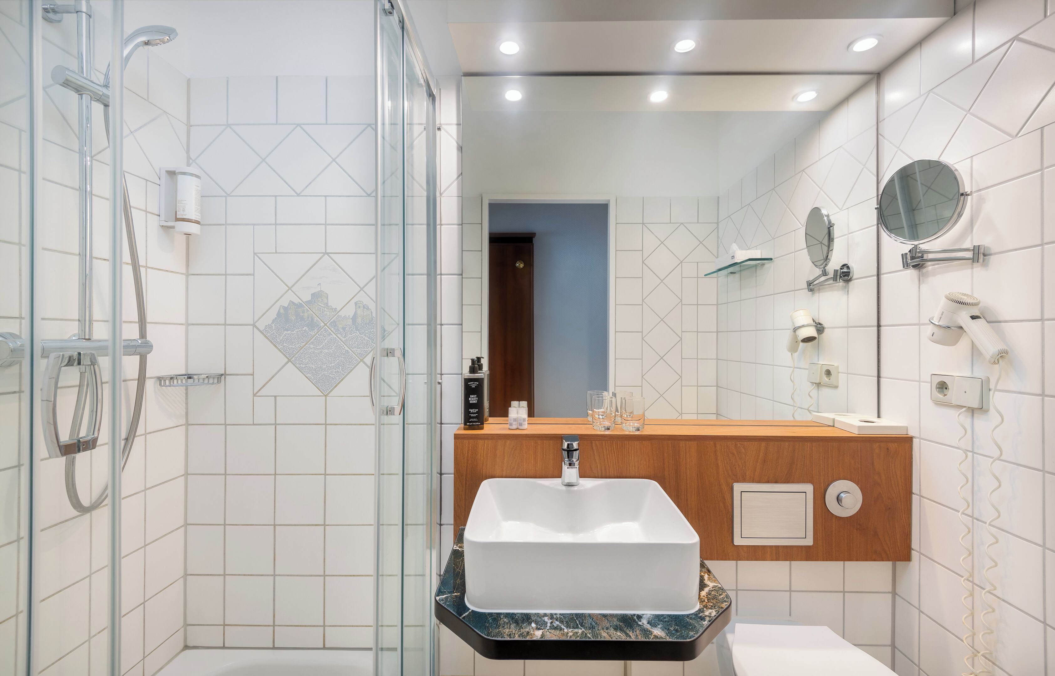 A modern bathroom with a glass shower enclosure, a wooden vanity with a white sink, and a mirror above the sink.