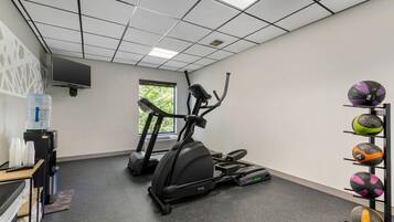 Un gimnasio con una máquina elíptica, una cinta de correr y un dispensador de agua.